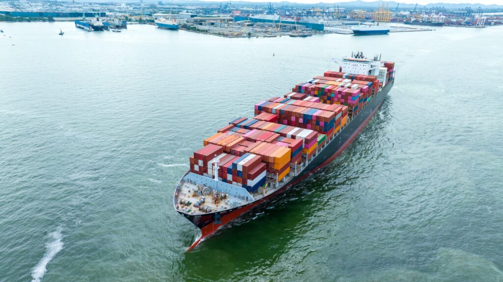 Aerial side view of cargo container ship carrying container from custom container depot