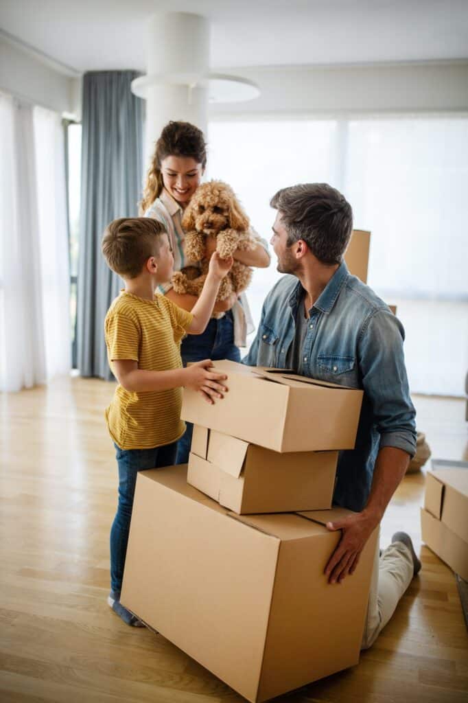 Happy family with children moving with boxes in a new apartment house